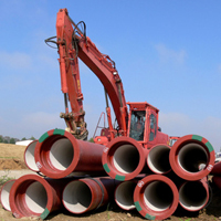 Bagger mit großen Rohren auf einer Baustelle