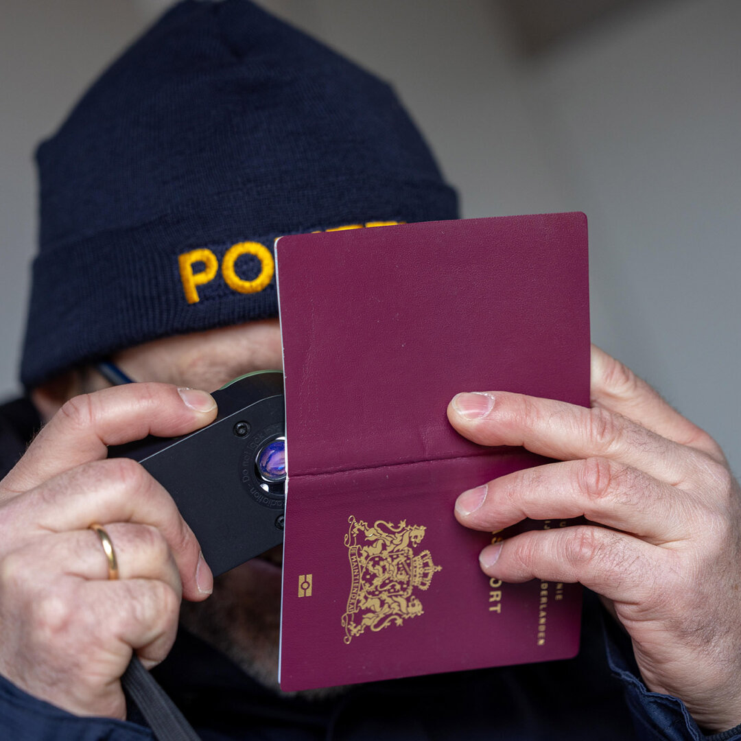 Ausweisprüfung bei einer Grenzkontrolle - © BayStMI ein Polizist mit einer Lupe der einen Reisepass genau mit der Lupe überprüft