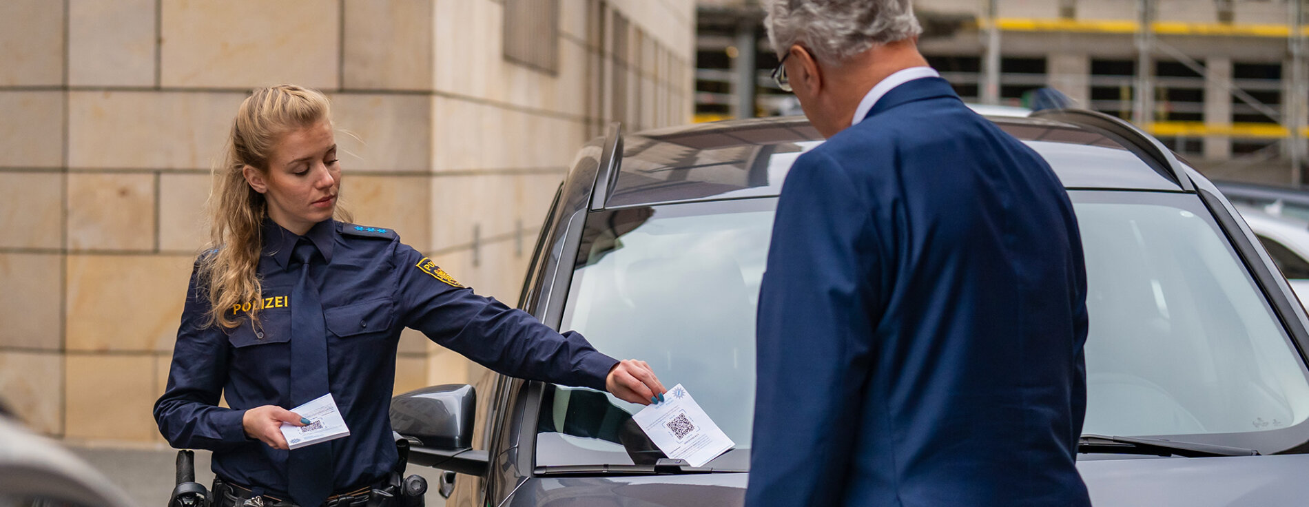 Mit der neuen mOwi-App können Verkehrsordnungswidrigkeiten durch die Polizei erfasst und von den Bürgern direkt auf einem neuen Bürger-Infoportal eingesehen und bezahlt werden. Polizistin steckt Strafzettel an Auto, Innenminister Joachim Herrmann von hinten