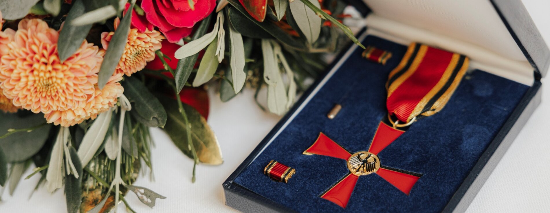 Verdienstkreuz am Bande des Verdienstordens der Bundesrepublik Deutschland Bundesverdienstkreuz in Schachtel und Blumenstrauß