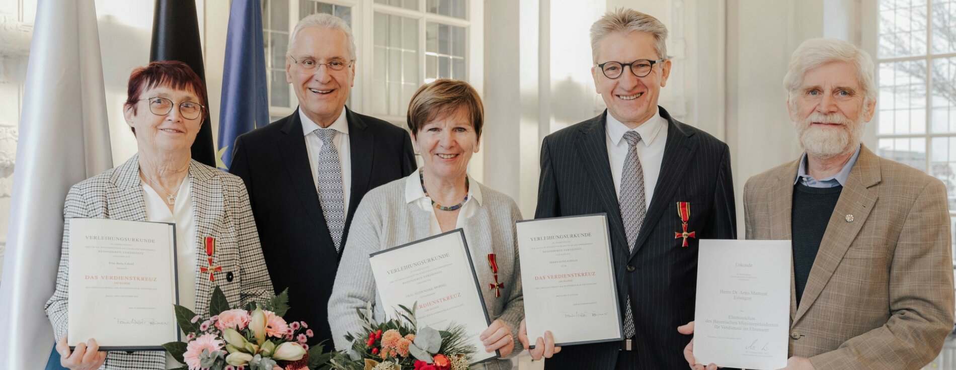 13. Dezember 2024: Bayerns Innen- und Kommunalminister Joachim Herrmann ehrte in Erlangen herausragendes Engagement: Berta Faßold, Heidemarie Sponsel und Hans Rebhan aus Mittelfranken wurden mit dem Verdienstkreuz am Bande des Verdienstordens der Bundesrepublik Deutschland ausgezeichnet, das Ehrenzeichen des Bayerischen Ministerpräsidenten für Verdienste im Ehrenamt erhielt Dr. Arno Mattejat aus Erlangen. Sie alle haben sich in besonderem Maße um das Gemeinwohl und um die Belange ihrer Mitmenschen verdient gemacht. Innenminister Joachim Herrmann mit Berta Faßold, Heidemarie Sponsel, Hans Rebhan und Dr. Arno Mattejat mit Urkunden, Verdienstkreuzen, Ehrenzeichen und Blumensträußen