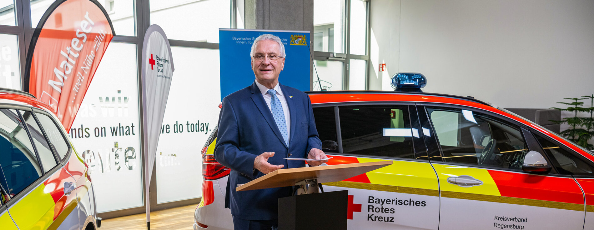 13. April 2022: Innenminister Joachim Herrmann startet Pilotprojekt mit neuem Rettungseinsatzfahrzeug in Regensburg: „Mit dem neuen Rettungseinsatzfahrzeug entlasten wir Notarzt und Rettungswagen bei weniger schwerwiegenden Einsätzen“, sagte Innenminister Joachim Herrmann bei der heutigen Vorstellung in Regensburg. „Mit den neuen Rettungseinsatzfahrzeugen stellen wir die Notfallversorgung unserer Bürgerinnen und Bürger auch in den nächsten Jahren weiterhin auf höchstem Niveau sicher.“ Innenminister Joachim Herrmann am Rednerpult zwischen zwei neuen Rettungseinsatzfahrzeugen